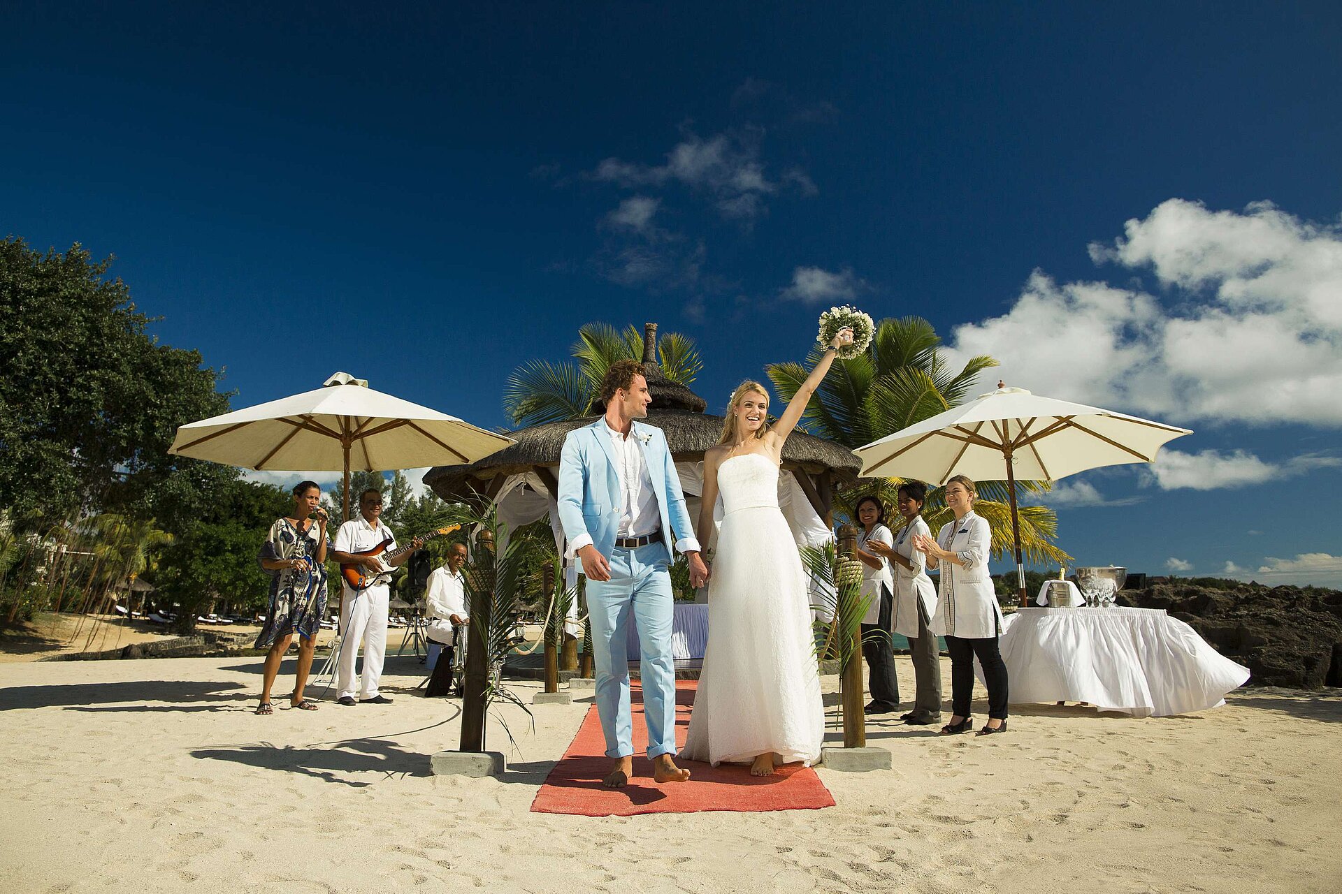 Wedding couple celebrating a beach wedding with guests, music and applause by the sea