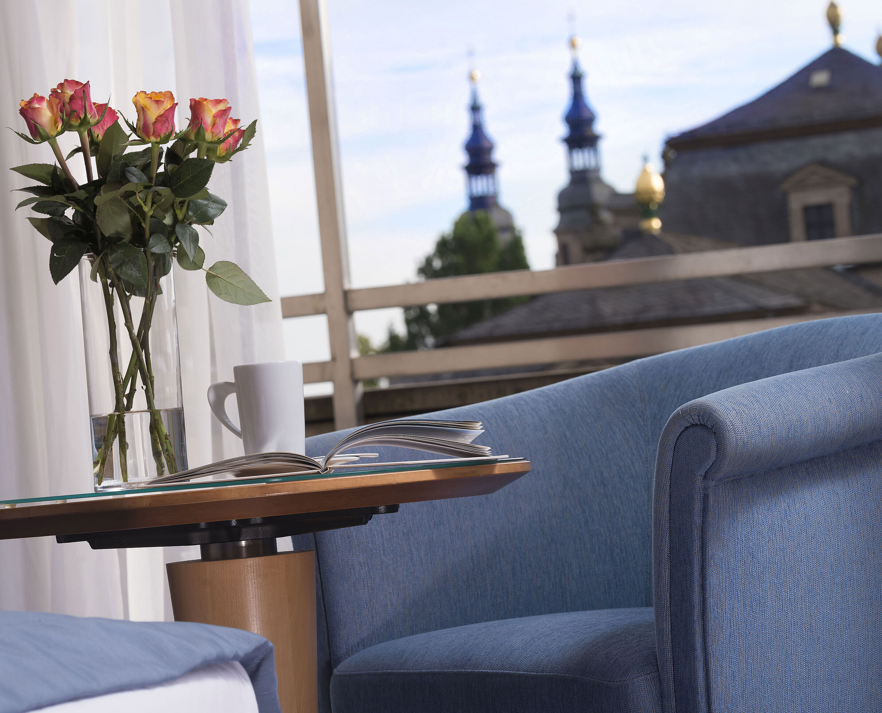 Elegant room detail at Maritim Hotel Fulda with blue seating, roses, and a view of the baroque towers of Fulda.