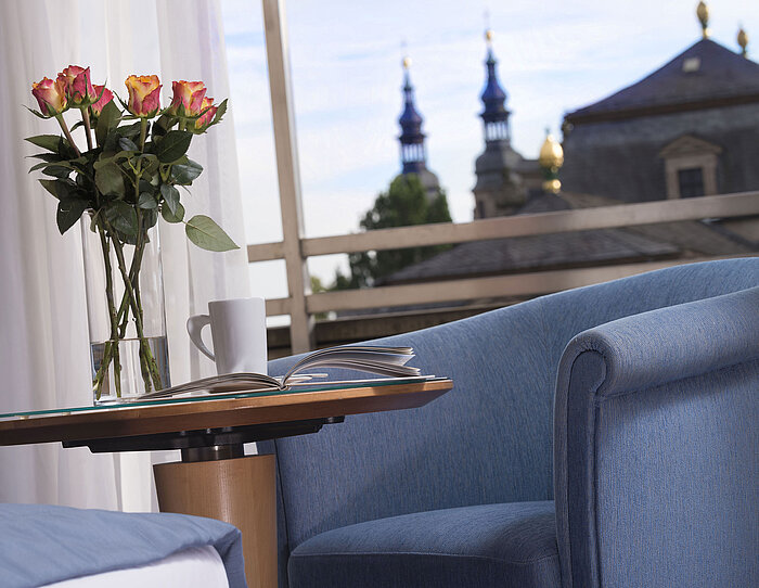 Elegant room detail at Maritim Hotel Fulda with blue seating, roses, and a view of the baroque towers of Fulda.