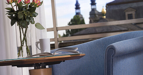Elegant room detail at Maritim Hotel Fulda with blue seating, roses, and a view of the baroque towers of Fulda.