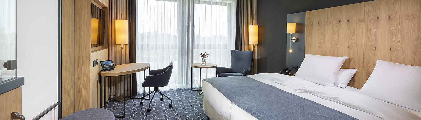 Spacious double room at Maritim Hotel Ingolstadt with desk, seating area, and balcony.