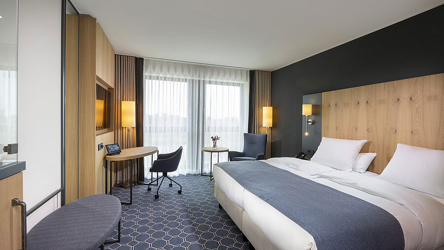 Spacious double room at Maritim Hotel Ingolstadt with desk, seating area, and balcony.