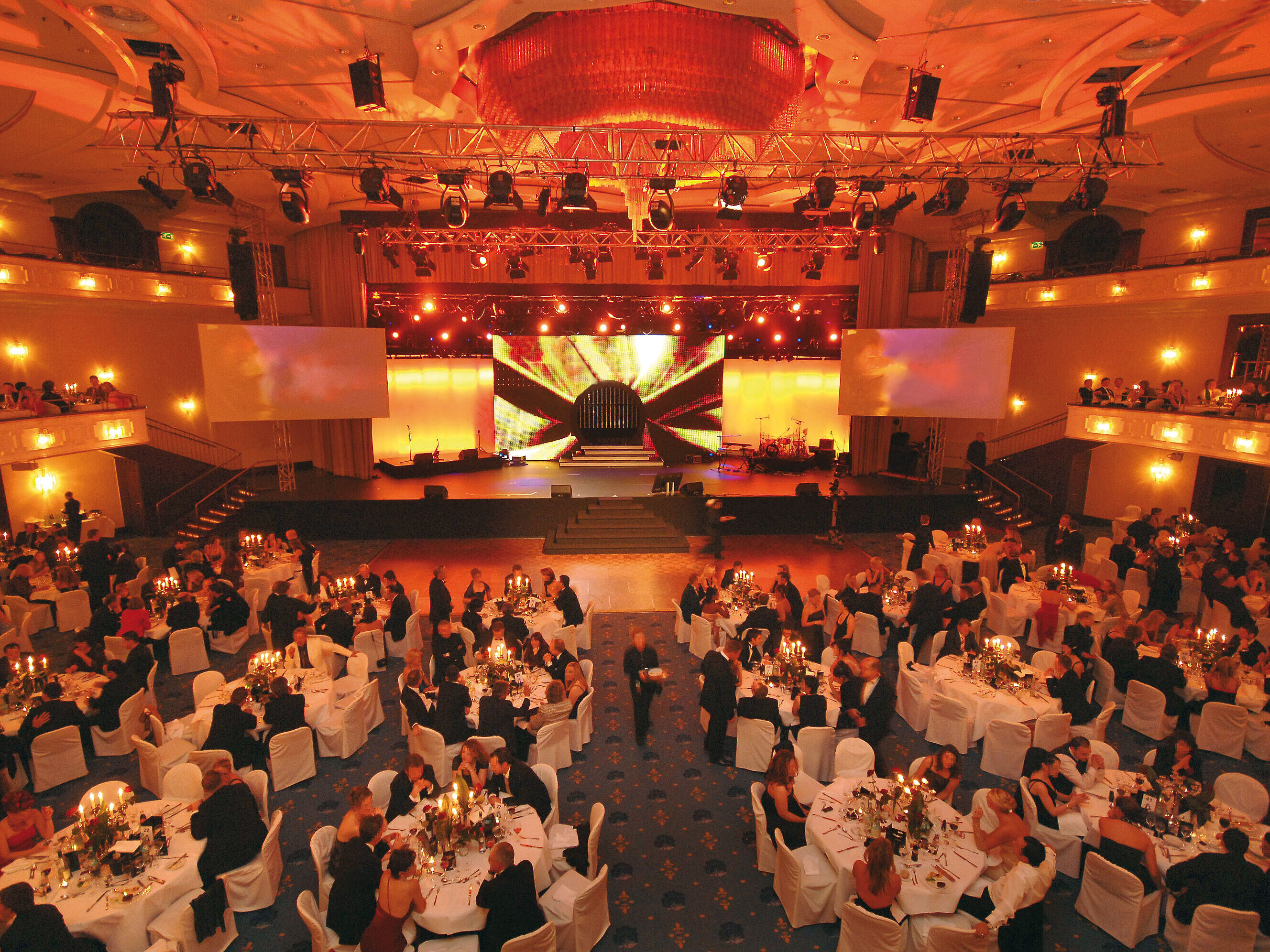 Festively lit event hall at Maritim Hotel Cologne with elegantly set tables and stage lighting.