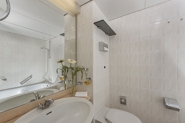 Bright bathroom at Maritim Hotel Bad Salzuflen with shower, large mirror and white tiles