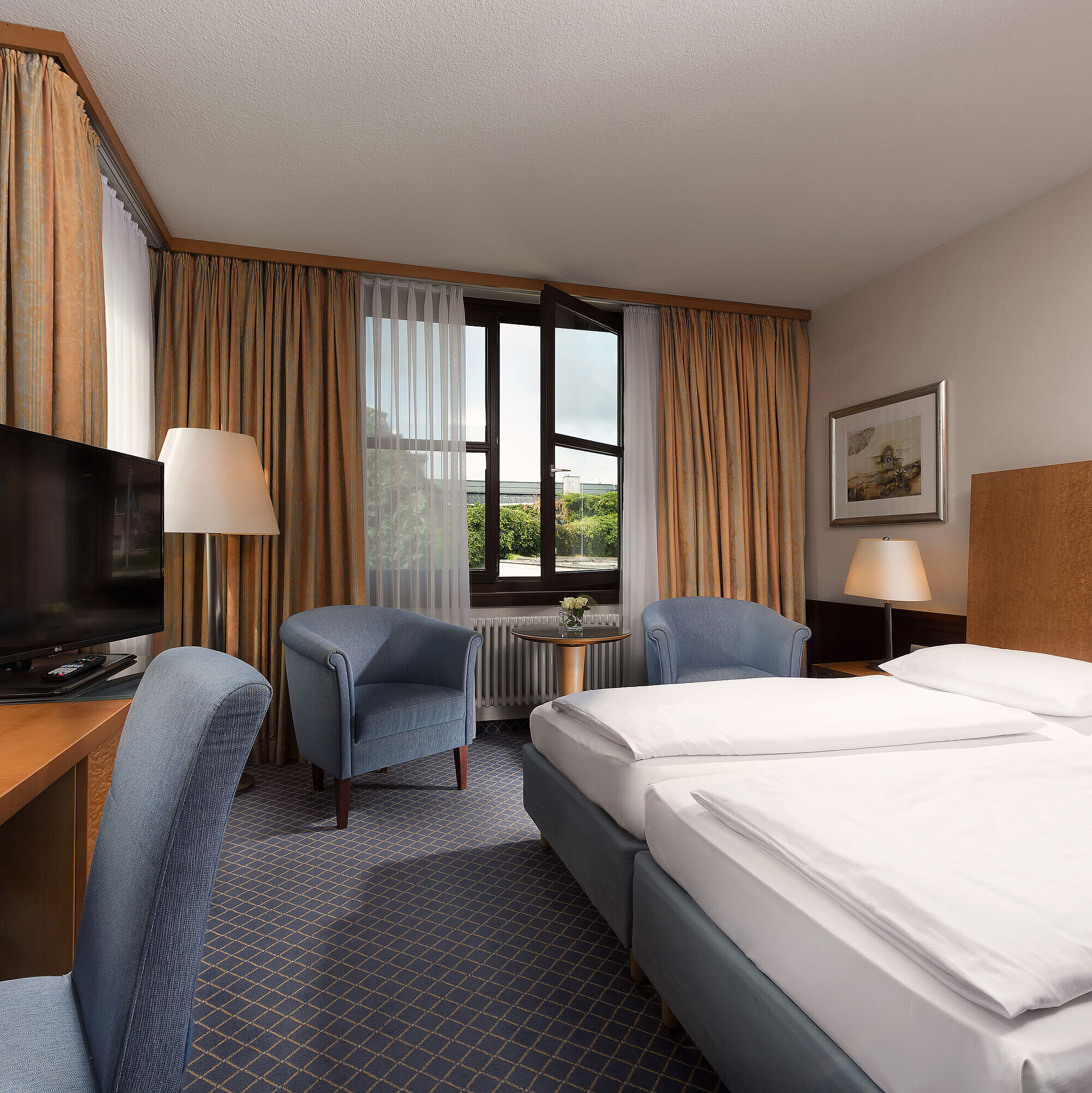 Classic room at Maritim Hotel Fulda with a cozy double bed, desk, seating area, and large window.