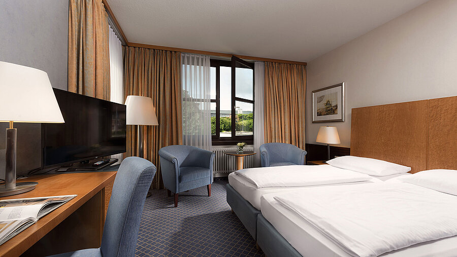 Classic room at Maritim Hotel Fulda with a cozy double bed, desk, seating area, and large window.
