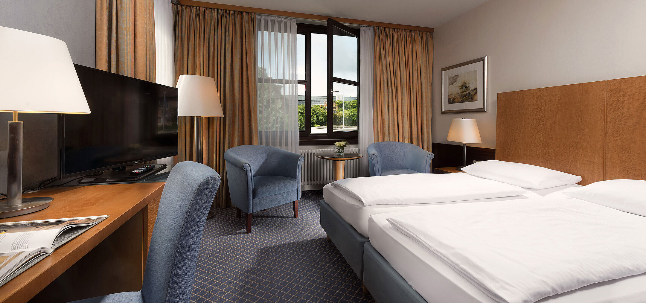 Classic room at Maritim Hotel Fulda with a cozy double bed, desk, seating area, and large window.