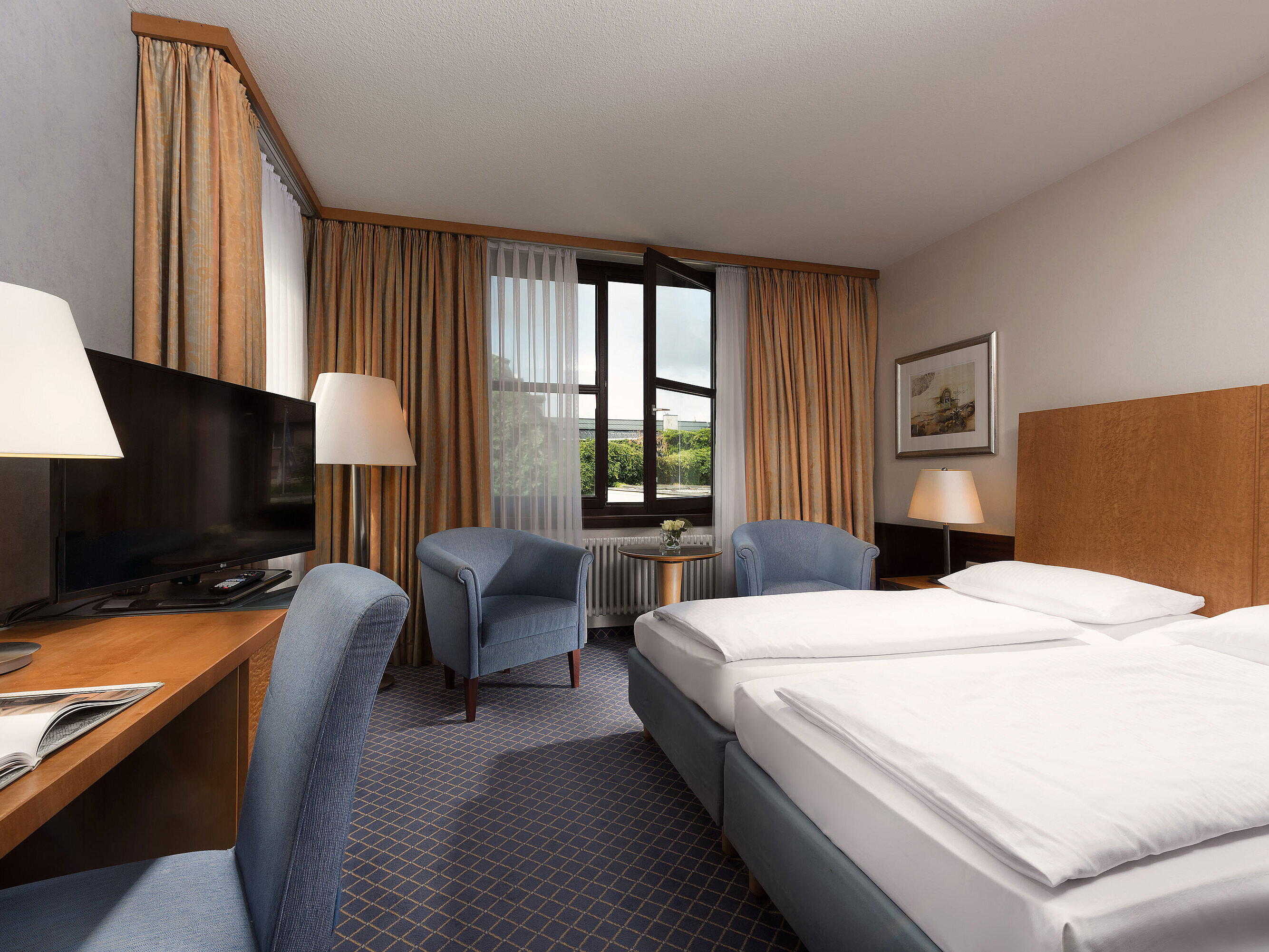 Classic room at Maritim Hotel Fulda with a cozy double bed, desk, seating area, and large window.