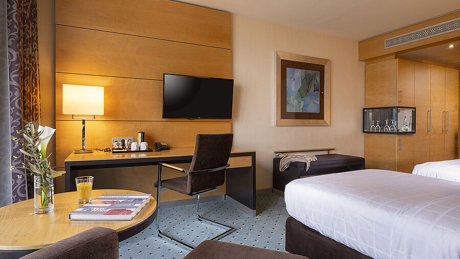Classic room at Maritim Hotel Düsseldorf with desk, flat-screen TV, double bed, and elegant decor.