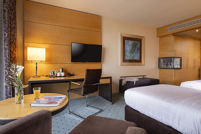 Classic room at Maritim Hotel Düsseldorf with desk, flat-screen TV, double bed, and elegant decor.