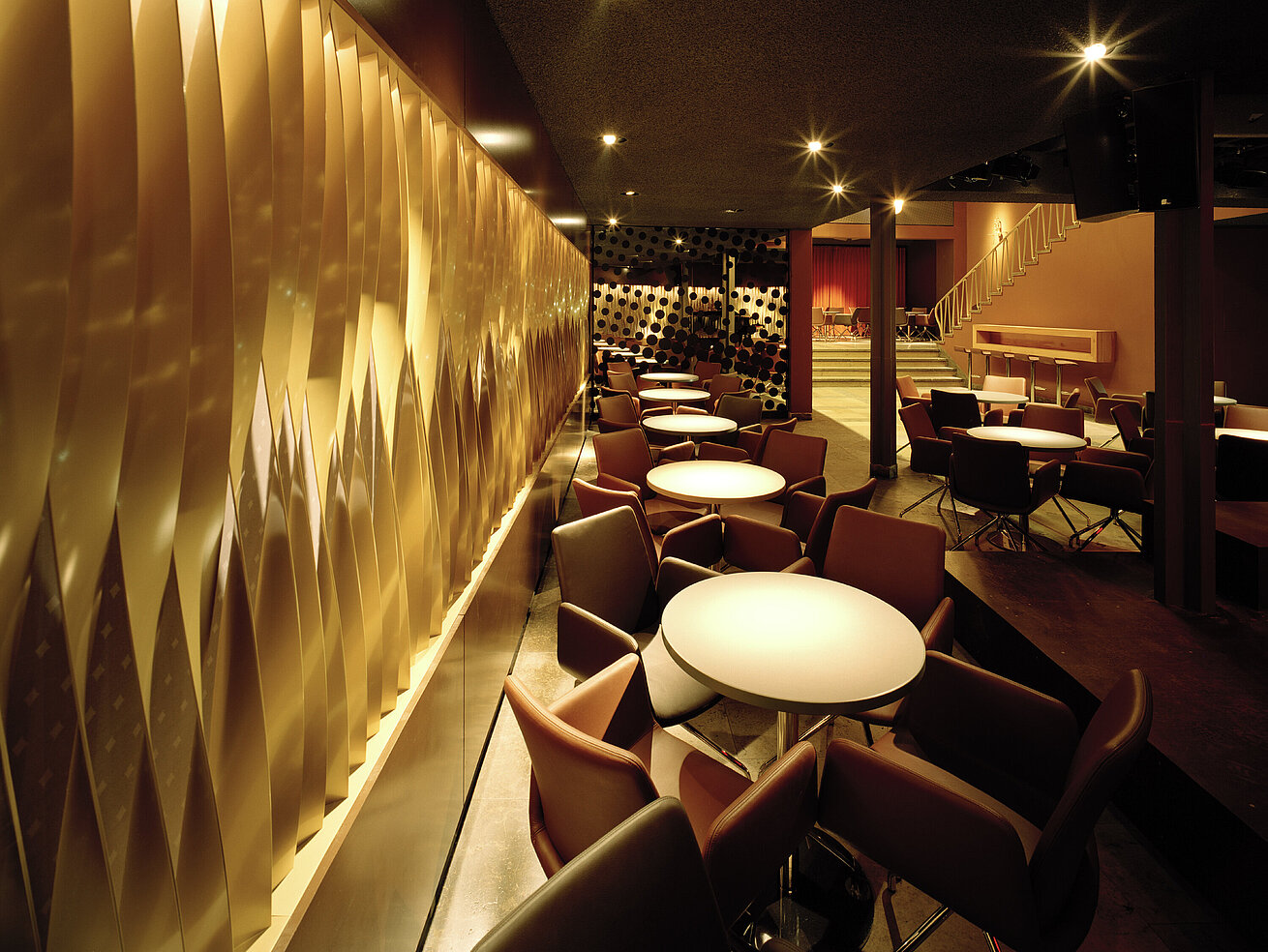 Modern lounge and bar area with round tables, warm lighting and stylish design
