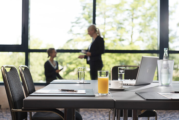 Modern meeting room with natural light, laptop, drinks, and informal conversation at Maritim Hotel Hannover.