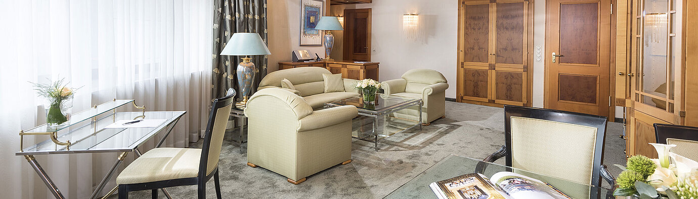 Spacious suite with elegant furnishings, glass table and cosy lounge at Maritim Hotel Magdeburg