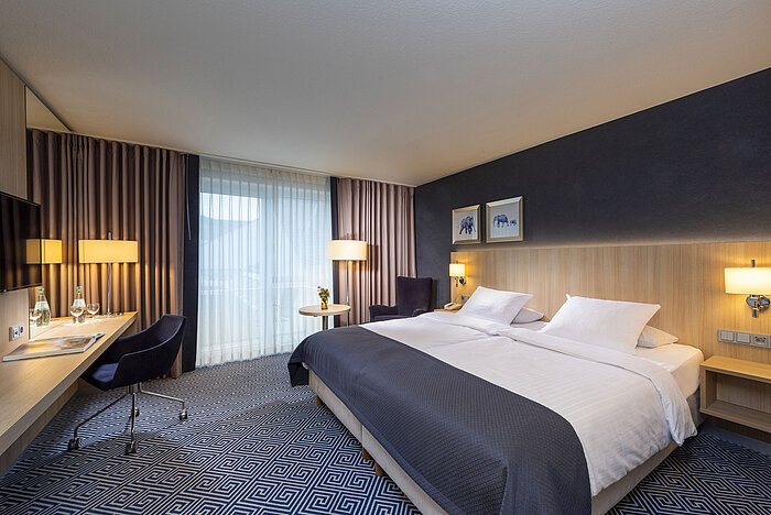 Spacious comfort room at Maritim Hotel Würzburg with desk, double bed and floor-to-ceiling windows