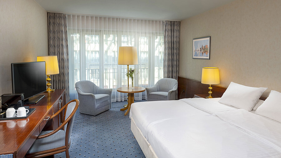 Classic room at the Maritim Hotel Cologne with a double bed, cozy seating area, desk, and TV.