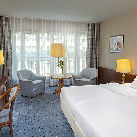 Classic room at the Maritim Hotel Cologne with a double bed, cozy seating area, desk, and TV.