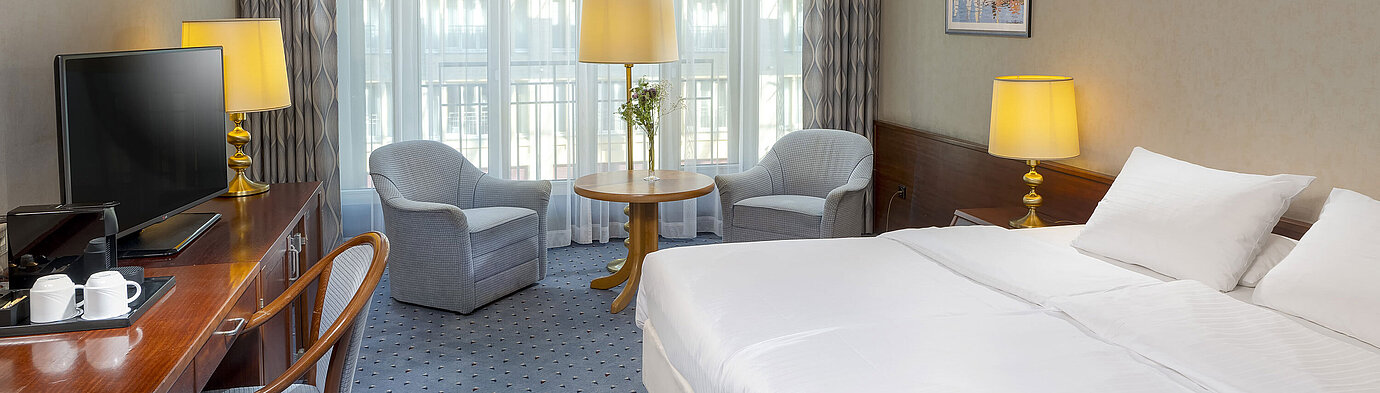 Classic room at the Maritim Hotel Cologne with a double bed, cozy seating area, desk, and TV.