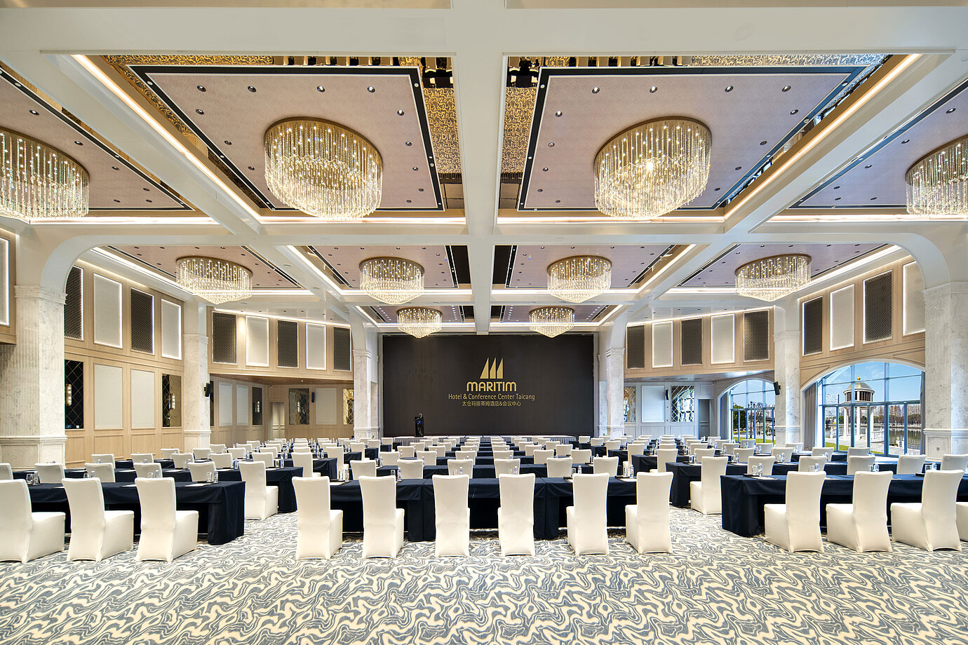 Bright Maritim Hotel ballroom with flexible seating, tall columns and modern chandeliers