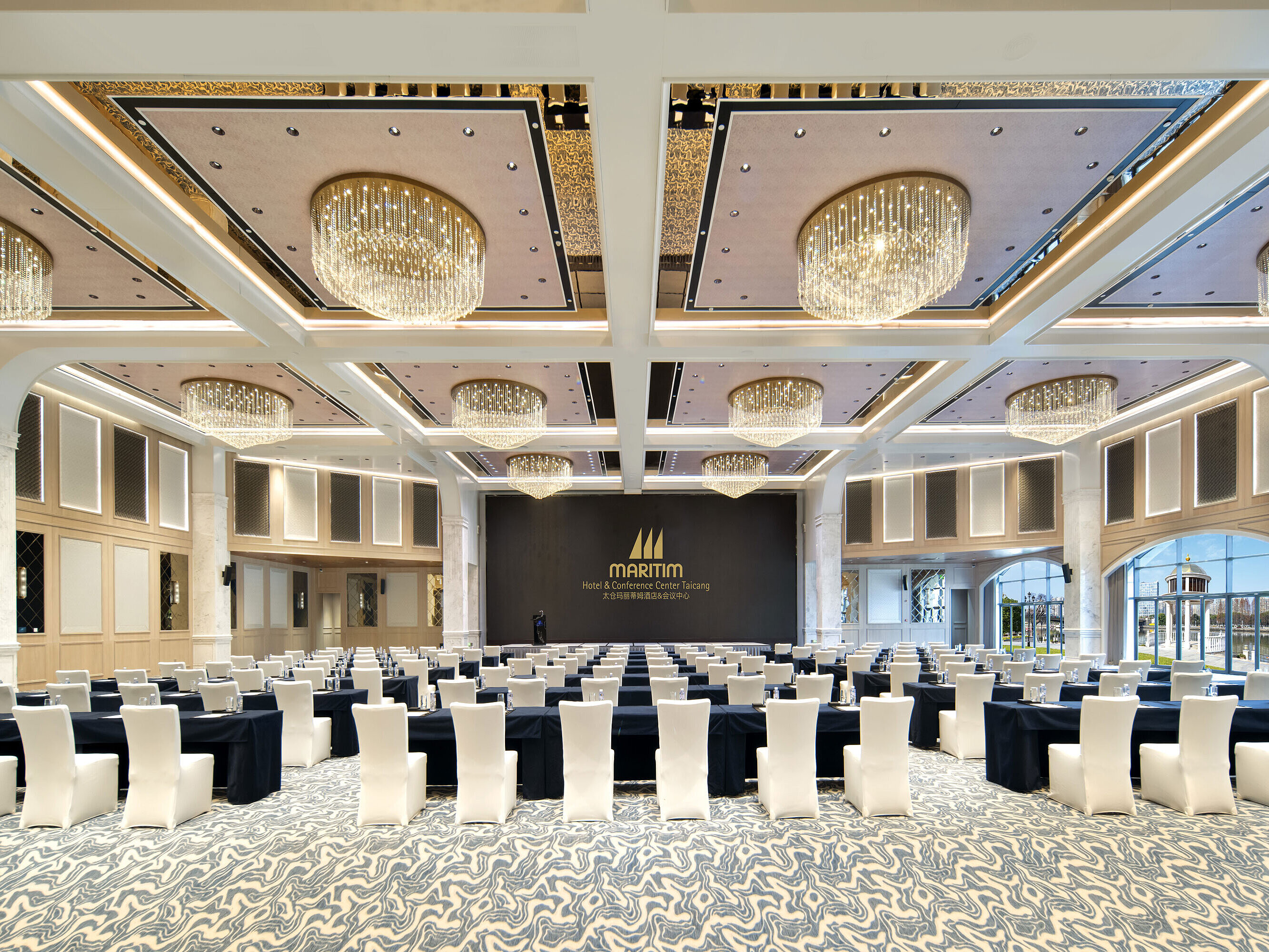Bright Maritim Hotel ballroom with flexible seating, tall columns and modern chandeliers