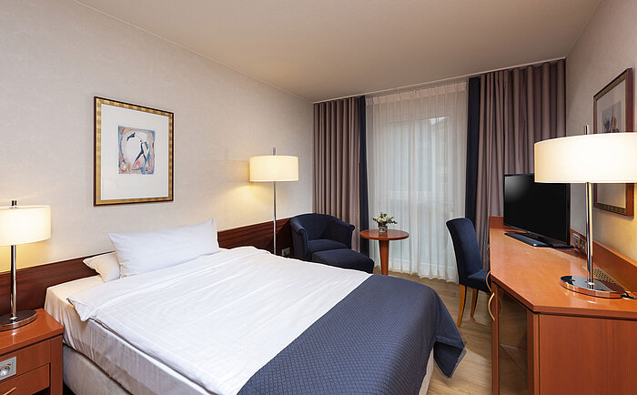 Classic single room at Maritim Hotel Würzburg with a cozy armchair and bright interior design