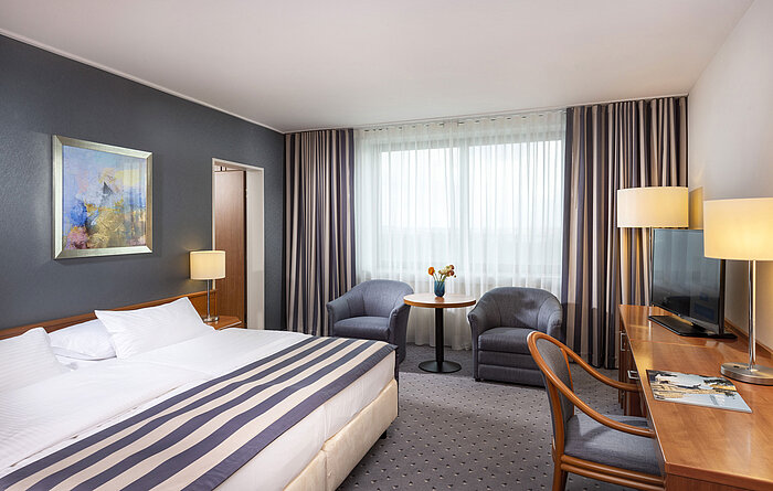Family room at Maritim Hotel Ulm with double bed, desk, seating area and plenty of natural light