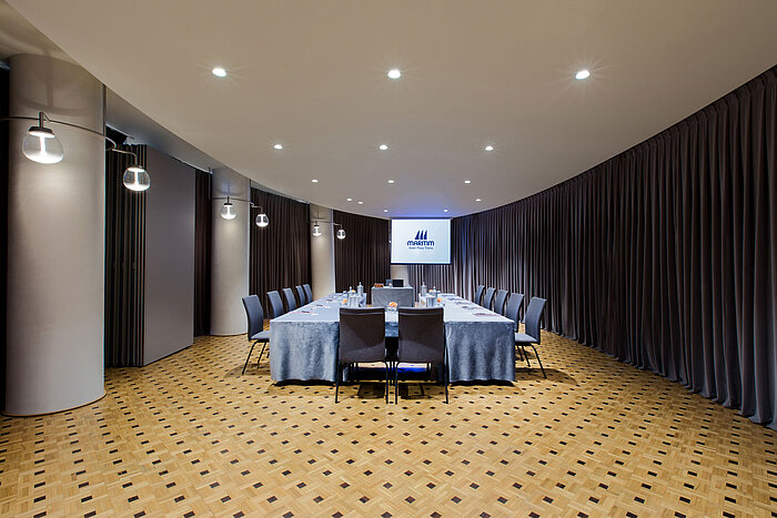 Modern meeting room at Maritim Hotel Plaza Tirana with U-shape seating, screen and elegant curtain design