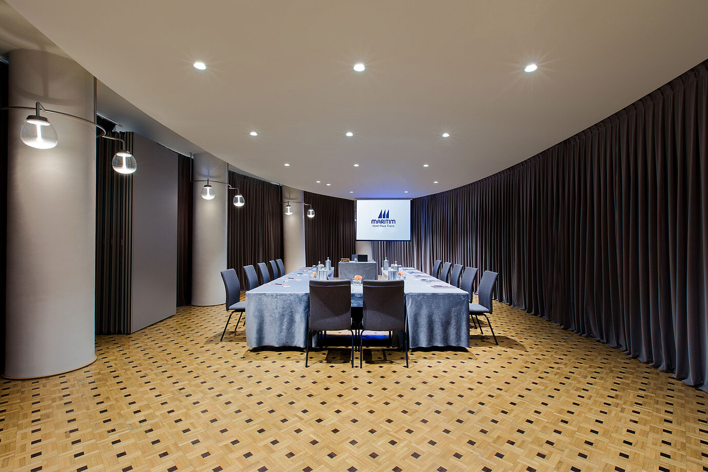 Modern meeting room at Maritim Hotel Plaza Tirana with U-shape seating, screen and elegant curtain design