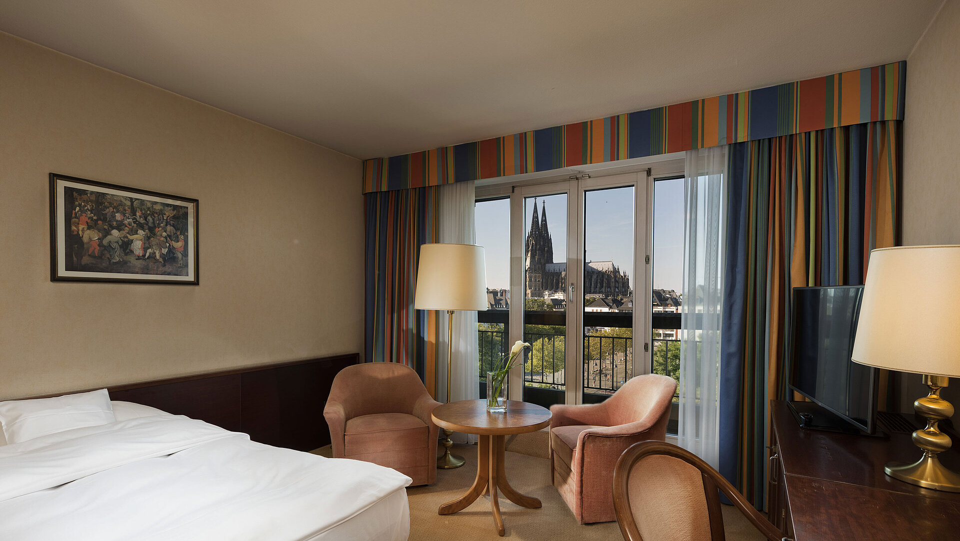 Superior room at Maritim Hotel Cologne featuring a seating area, comfortable bed, and view of Cologne Cathedral.