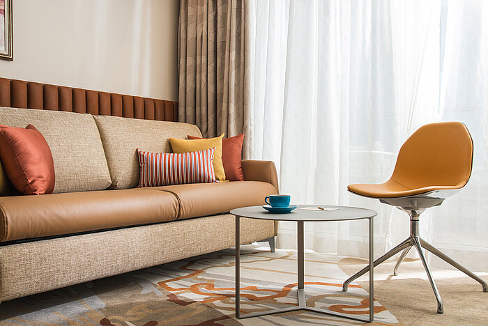 Modern living area at Maritim Hotel Amelia with sofa, colourful cushions, chair and table