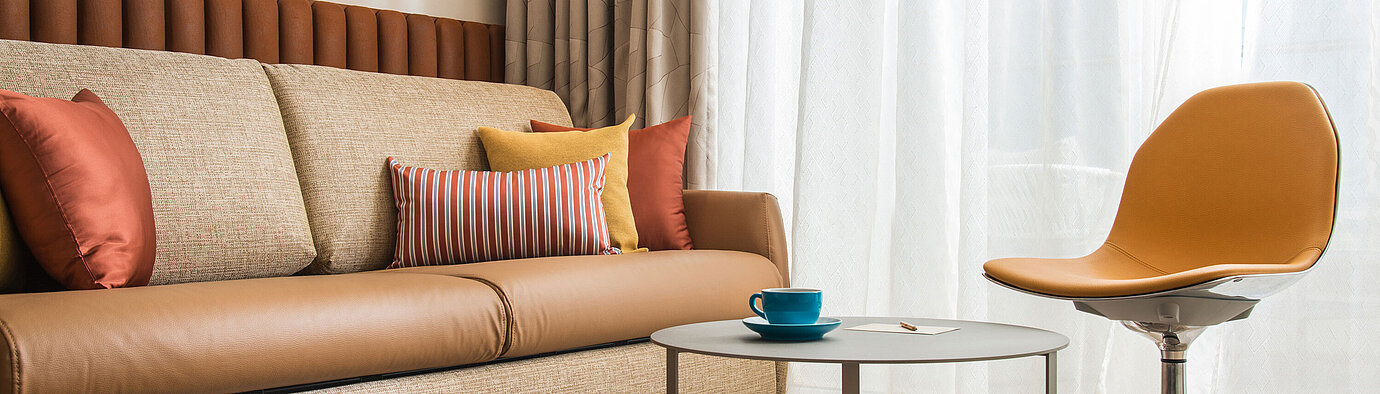 Modern living area at Maritim Hotel Amelia with sofa, colourful cushions, chair and table