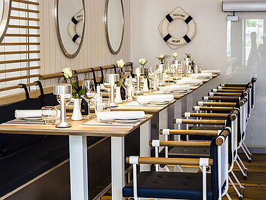 Modern restaurant with long table, maritime décor and stylishly set places