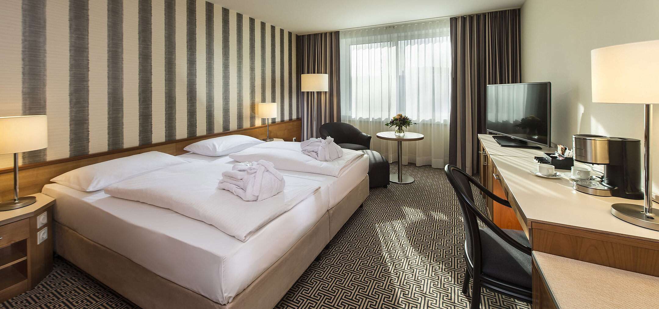 Bright double room with desk, armchairs and large bed at the Maritim Hotel Stuttgart