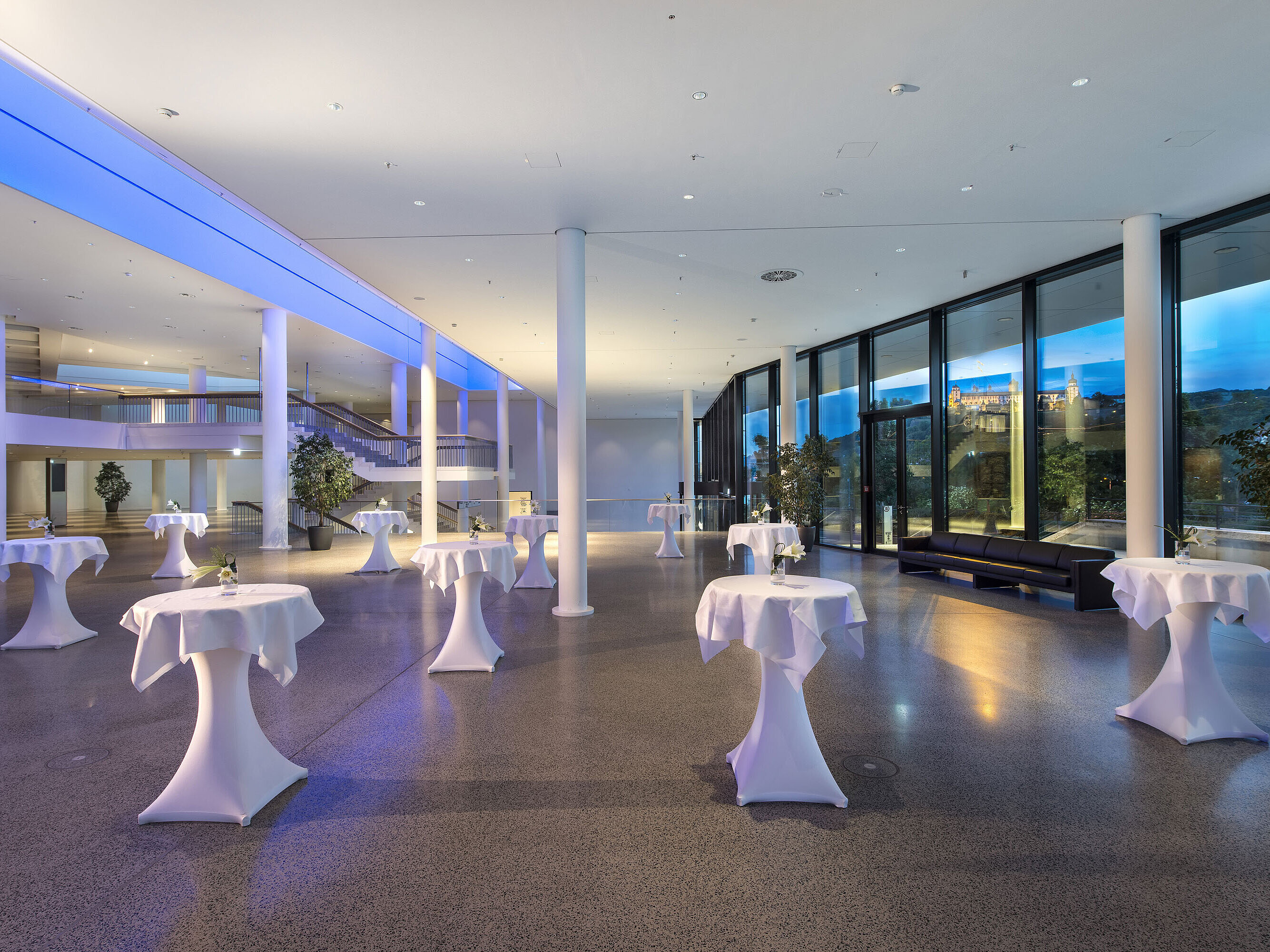 Modern foyer at Maritim Hotel Würzburg with high tables, large windows and fortress view
