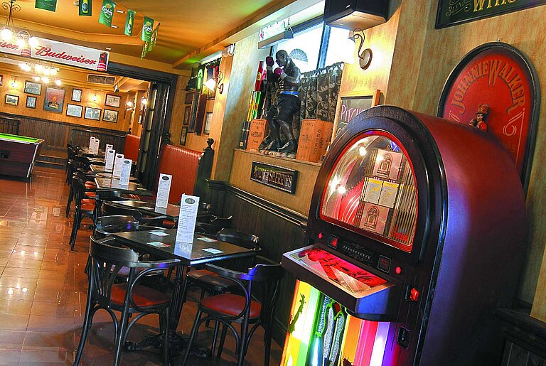 Cosy bar with jukebox, tables and chairs, warm lighting and classic pub atmosphere