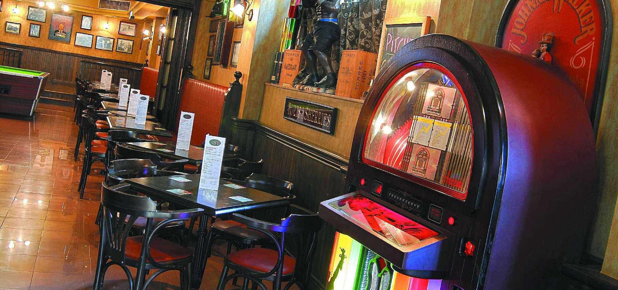 Cosy bar with jukebox, tables and chairs, warm lighting and classic pub atmosphere