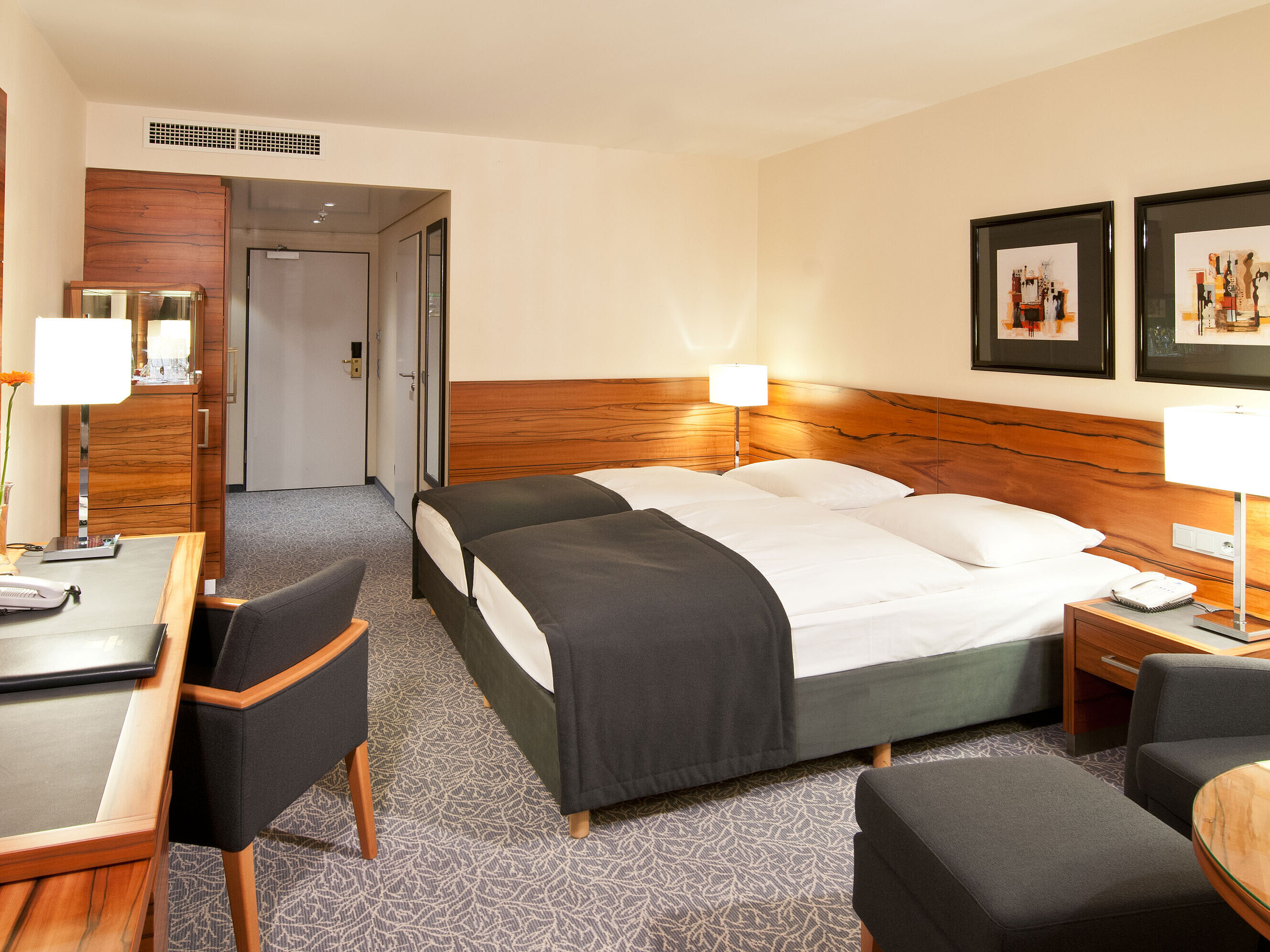 Double room with wood accents, seating area and desk at Maritim Hotel Munich