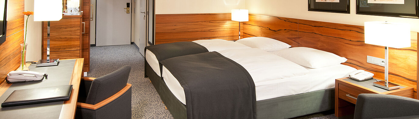 Double room with wood accents, seating area and desk at Maritim Hotel Munich