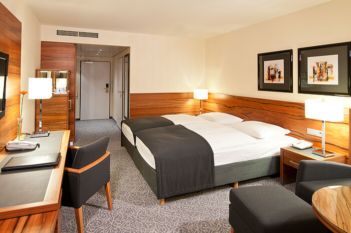 Double room with wood accents, seating area and desk at Maritim Hotel Munich