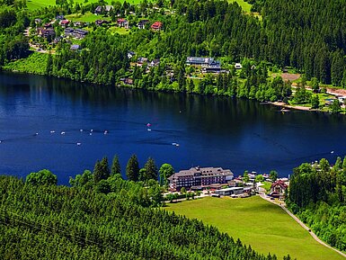 Aerial view of the Maritim Hotel on Lake Titisee with surrounding forest and pedal boats on the water