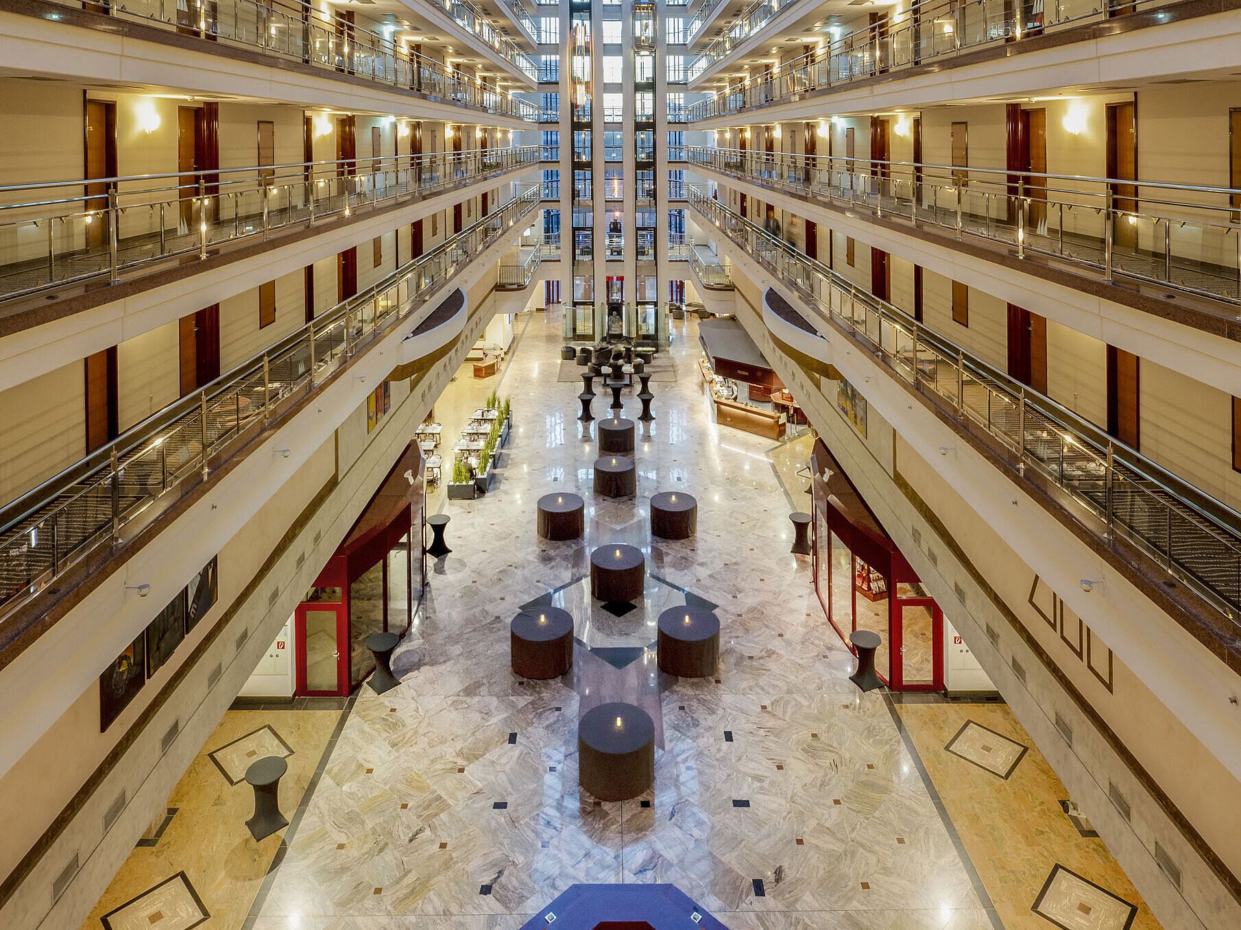 Impressive hotel lobby with glass ceiling, multiple floors, and seating areas, creating a spacious and elegant ambiance