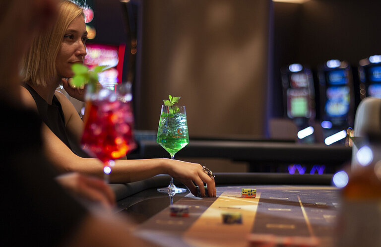 Woman with cocktail and chips at gaming table in the casino of Maritim Hotel Plaza Tirana