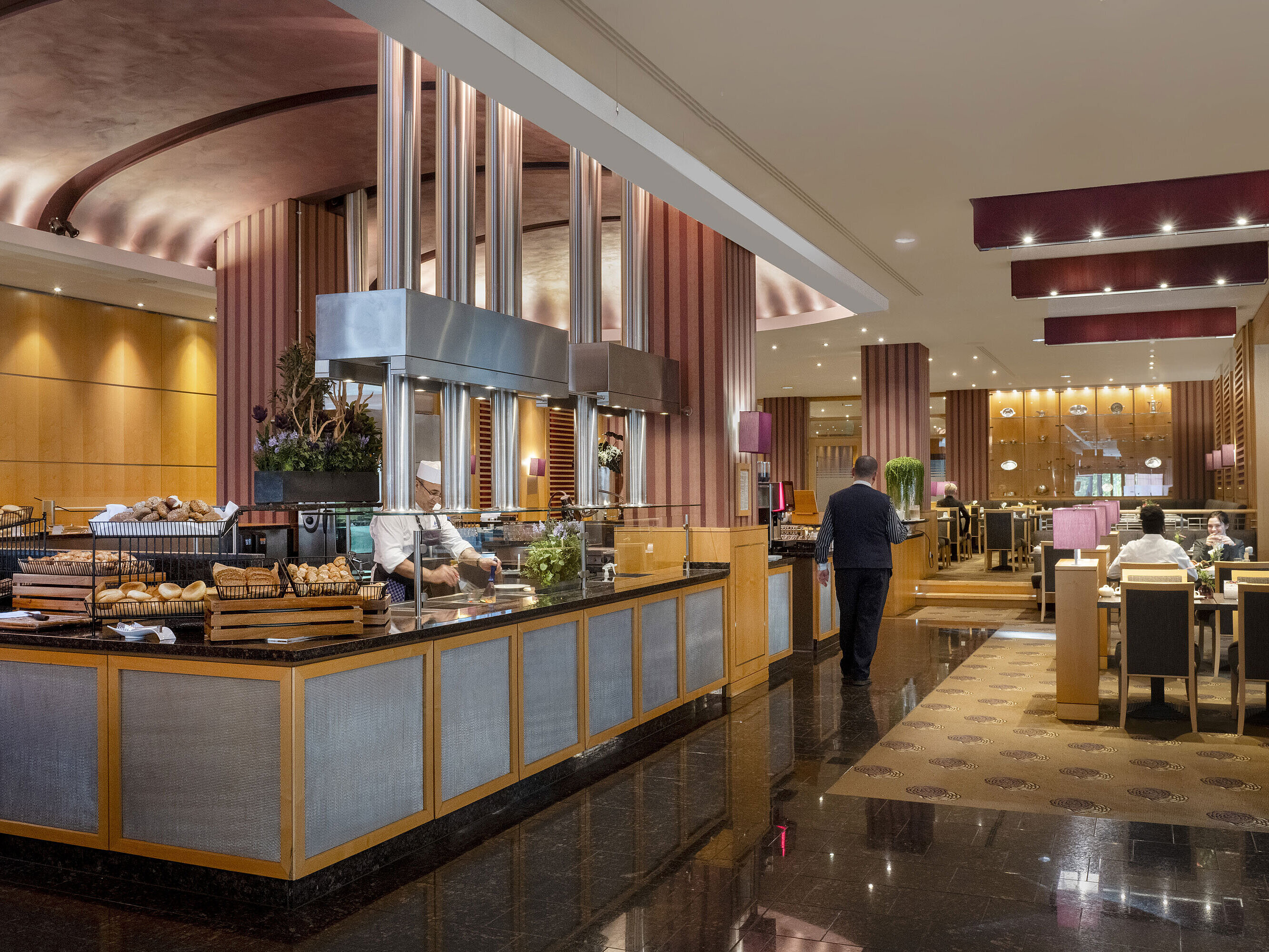 Breakfast area at Maritim Hotel Düsseldorf with live cooking station, fresh baked goods, and elegant interior design.