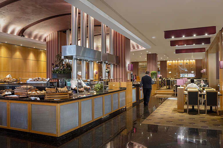 Breakfast area at Maritim Hotel Düsseldorf with live cooking station, fresh baked goods, and elegant interior design.