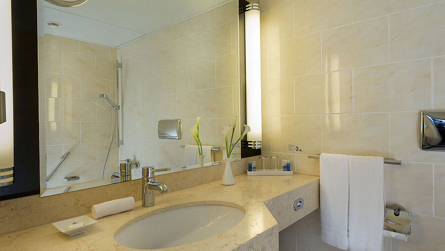 Modern bathroom at Maritim Hotel Fulda with marble sink, large mirror, and walk-in shower.