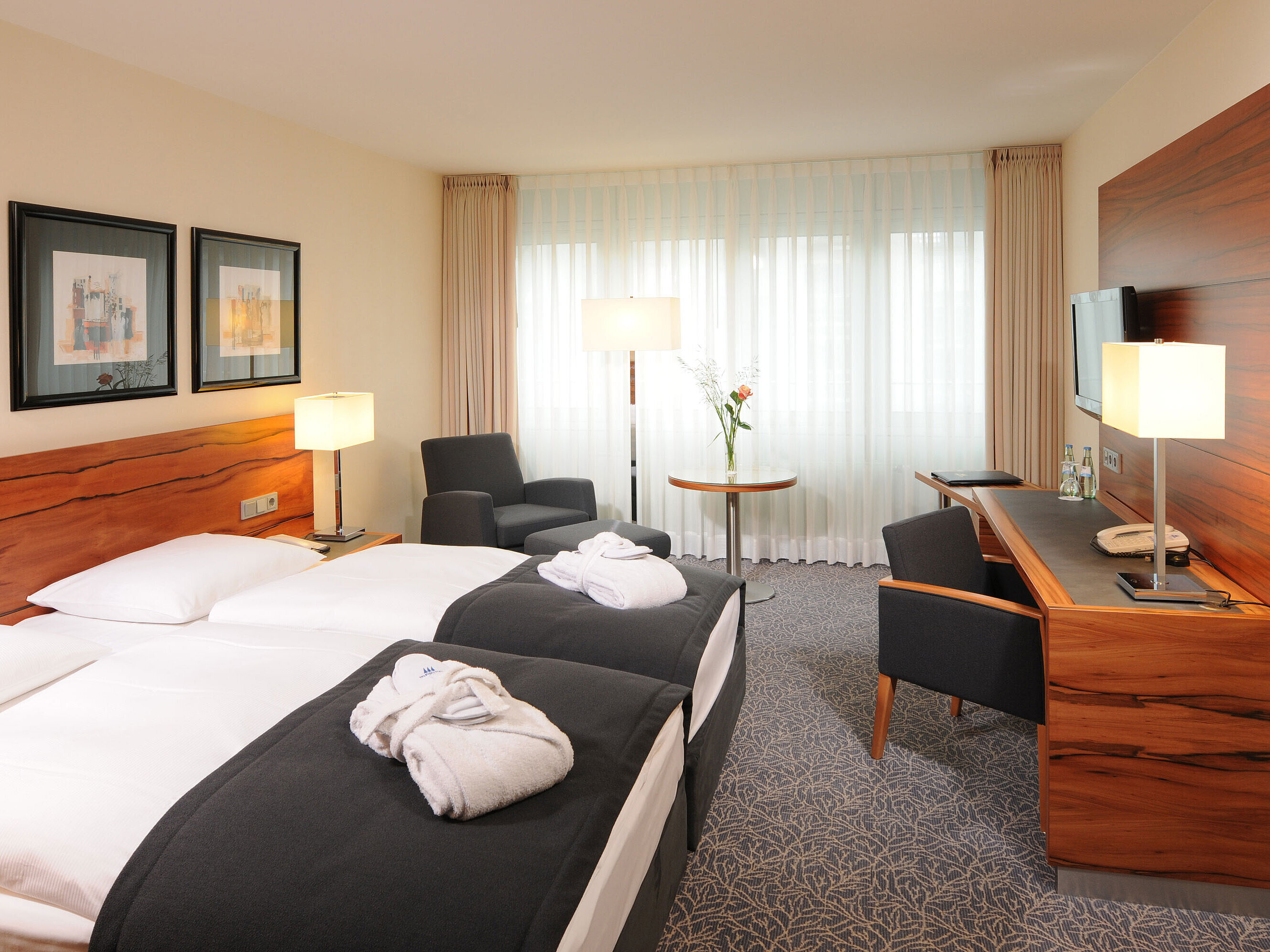 Bright double room with desk, armchairs and bathrobes at Maritim Hotel Munich