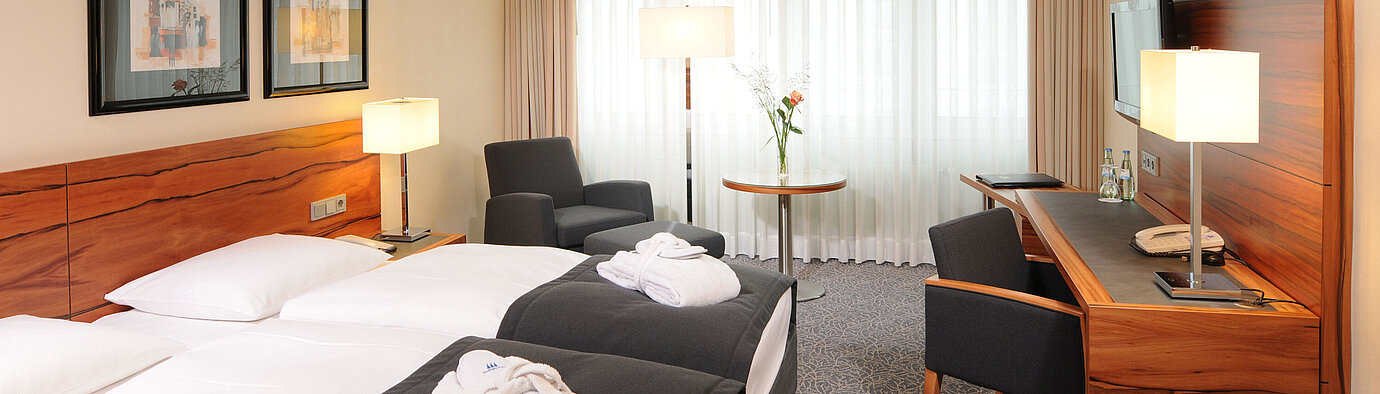 Bright double room with desk, armchairs and bathrobes at Maritim Hotel Munich