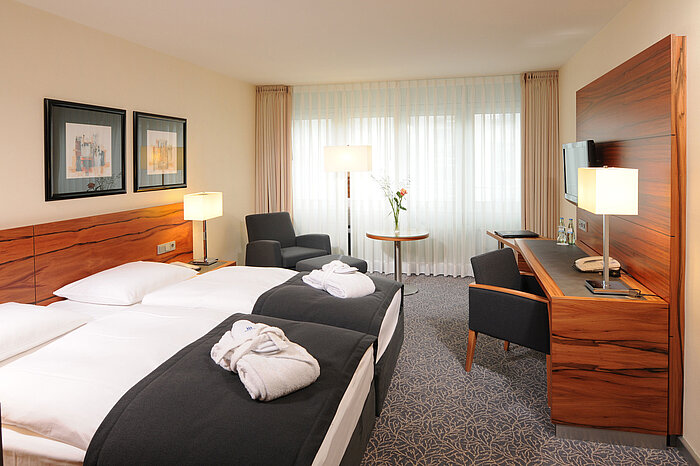 Bright double room with desk, armchairs and bathrobes at Maritim Hotel Munich