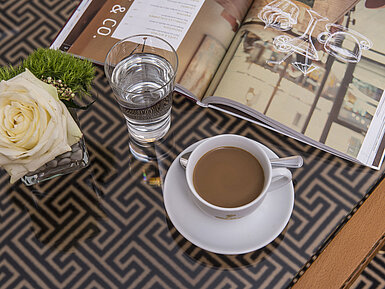 Close-up with rose, coffee, water and magazine on glass table at the Maritim Hotel Stuttgart