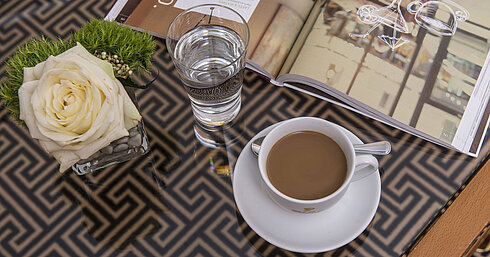 Close-up with rose, coffee, water and magazine on glass table at the Maritim Hotel Stuttgart