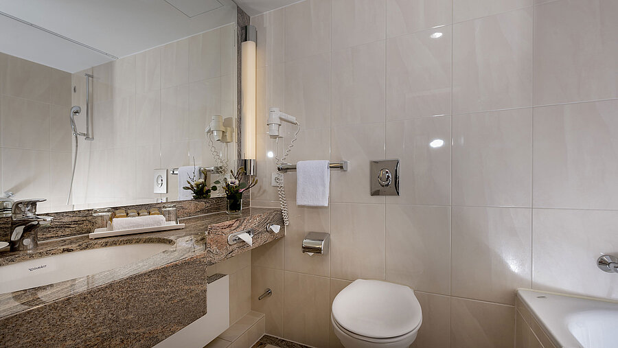 Modern bathroom at Maritim Seehotel Timmendorfer Strand with sink, mirror, shower, toilet, and bathtub.
